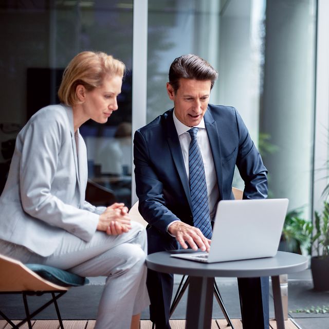 Two business professionals in a modern office environment are reviewing Telekom’s IoT reference cases on a laptop.