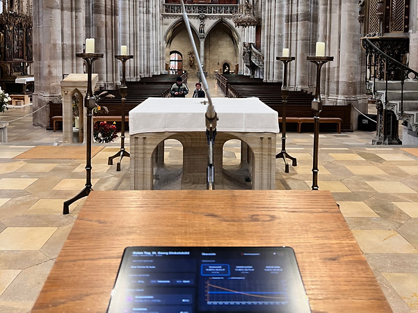 A church interior with an altar, a microphone and a digital control panel in the foreground.