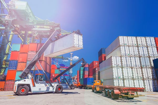 Container stacker places containers on a transport truck