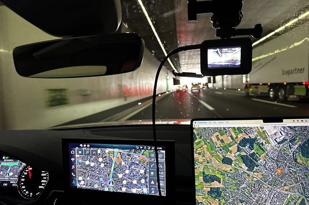 Fahrt durch den Gotthard-Straßentunnel, Displays von Navi und Laptop mit Route