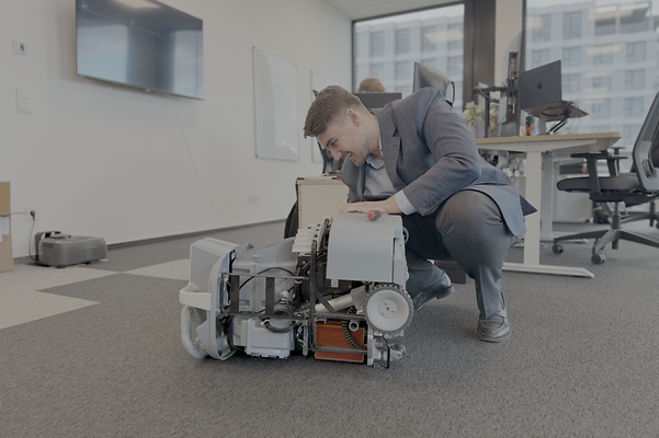 Nick Nidens repariert einen automomen Reinigungsroboter in einem Büroraum.