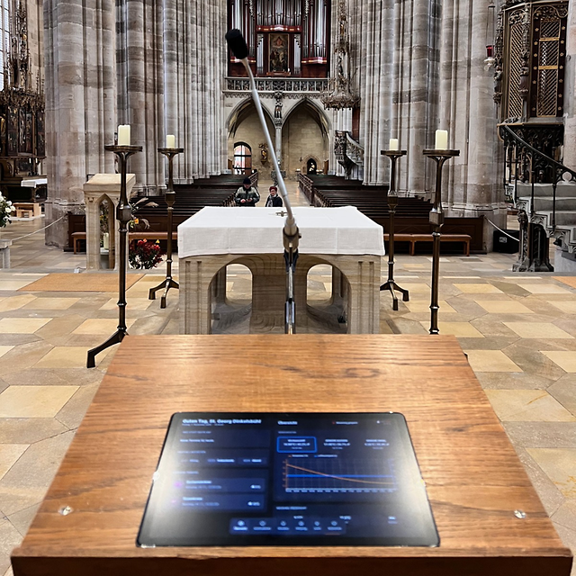 A church interior with an altar, a microphone and a digital control panel in the foreground.