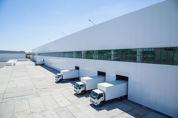 En lastbilsflotta framför ett logistikcenter.