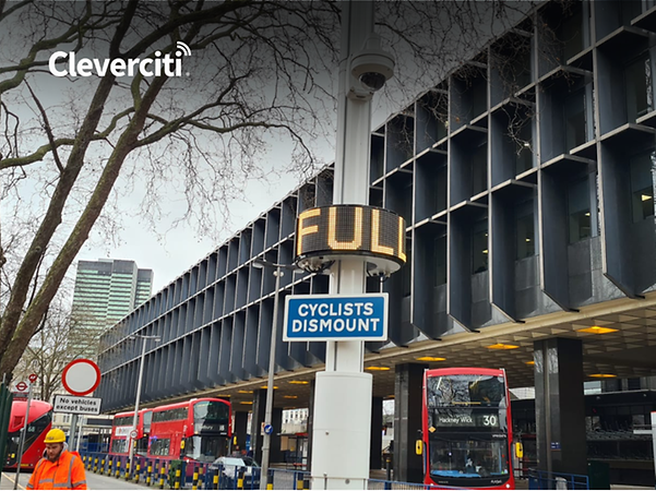 Cleverciti-logotypen framför ett parkeringshus med en skylt som visar ”Fullt” och röda bussar