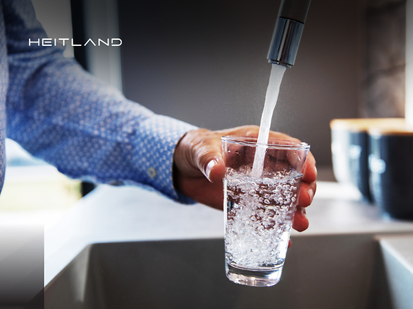Logotipo de Heitland delante de una persona que llena un vaso con agua del grifo