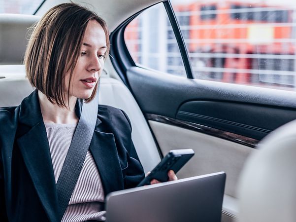 A businesswoman sits in a car with HotSpot Drive