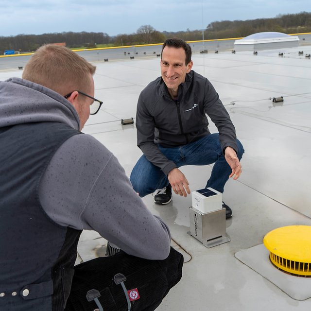 Sita’s CEO demonstrates a flat-roof monitoring device to customers.