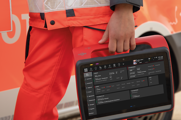 En ambulanssjukvårdare står framför en ambulans och håller i en surfplatta där den digitala uppdragsdokumentationen visas.