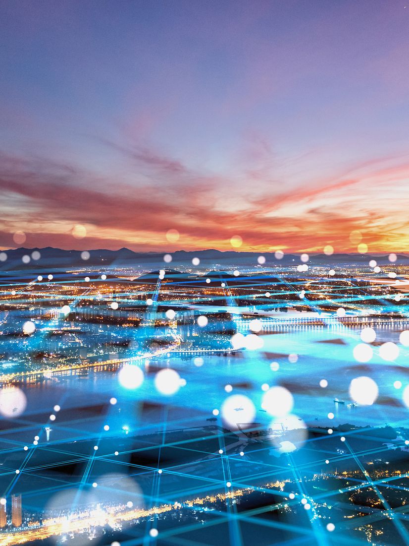 Luftaufnahme einer Stadt mit einem digitalen Netzwerk aus blauen Linien, das die Digitalisierung darstellt.