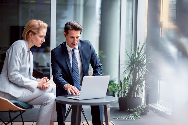 Zwei Personen im modernen Büro schauen am Laptop die Referenzen der Telekom IoT an.