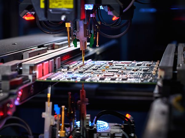 Roboterarm mit IoT Hardware montiert elektronische Bauteile in moderner Fertigungsumgebung.