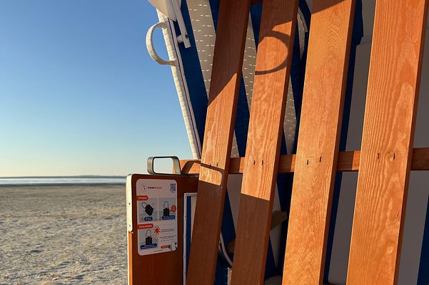 Strandkorb auf Sand mit Meer im Hintergrund