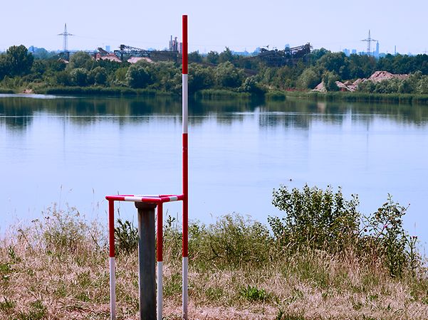 Messstelle zur Überwachung des Grundwasserspiegels und der Wasserqualität eines Baggersees.