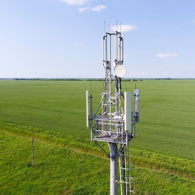 Funkmast mit Mobilfunkantennen auf einem Feld