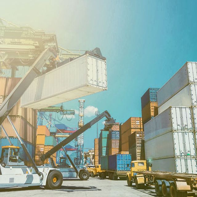 Ein Kran stapelt einen IoT-vernetzten Container auf einem Containerdepot