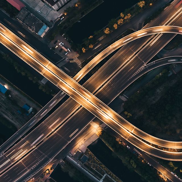 Luftaufnahme eines beleuchteten Autobahnkreuzes.
