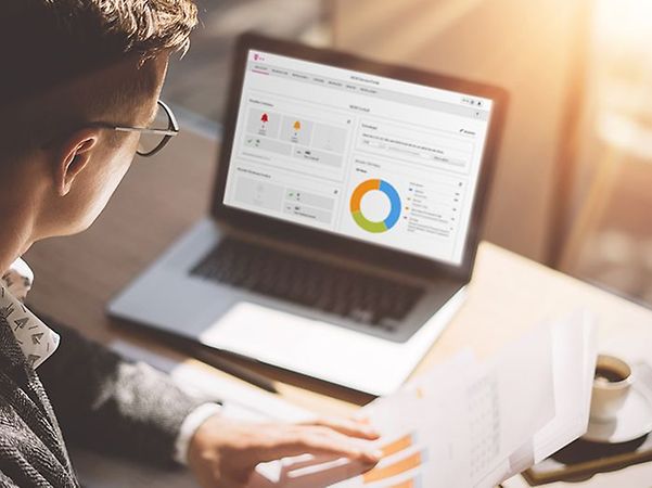 Eine Person betrachtet auf einem Laptop eine Datenanalyse mit Diagrammen zum IoT M2M Service Portal.