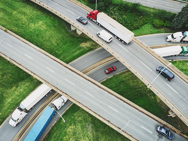Drohnenaufnahme: ein Autobahnkreuz von oben mit einigen LKWs und PKWs