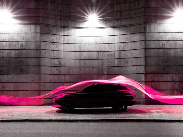 Modern car illuminated by magenta light trails symbolizing digital connectivity.
